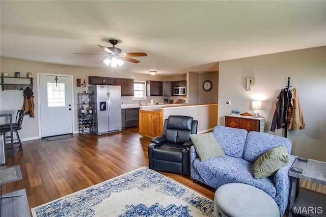 living area featuring healthy amount of natural light, a ceiling fan, dark wood finished floors, and baseboards