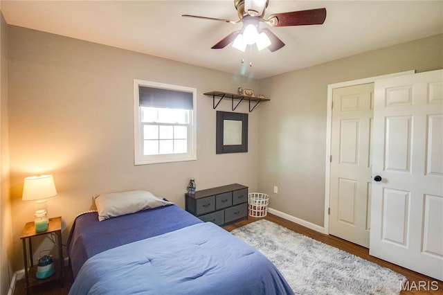 bedroom featuring baseboards, wood finished floors, and ceiling fan