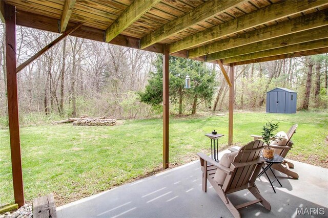view of patio featuring a storage shed, an outbuilding, and a wooded view