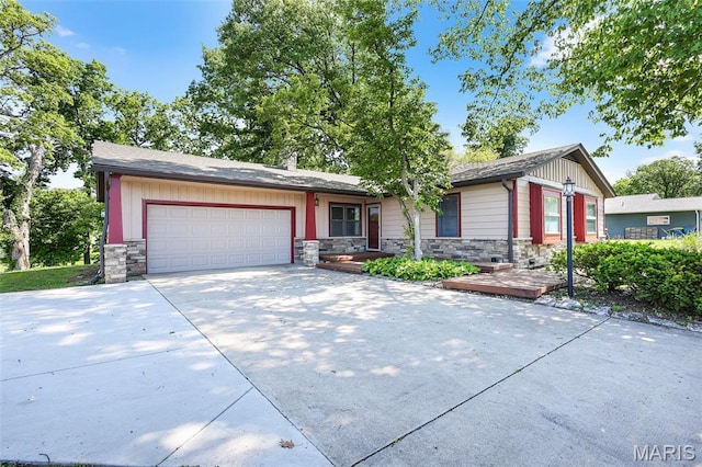 135 Hollyhock Ln, Edwardsville, IL 62025 - ranch-style house with stone siding, an attached garage, concrete driveway, and board and batten siding