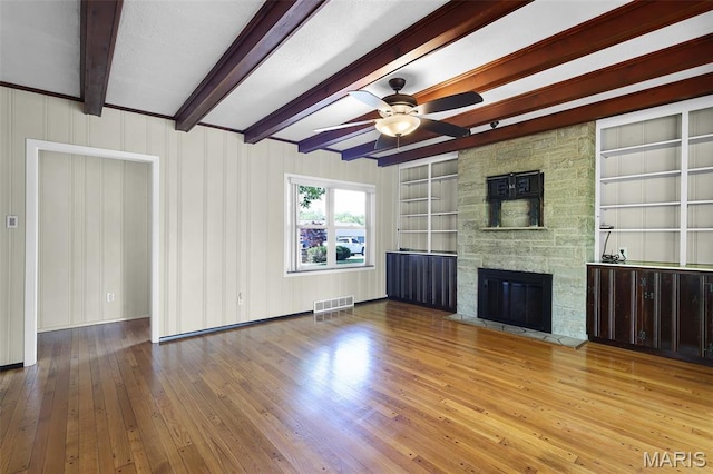135 Hollyhock Ln, Edwardsville, IL 62025 - unfurnished living room featuring hardwood / wood-style flooring, ceiling fan, beam ceiling, a stone fireplace, and built in shelves