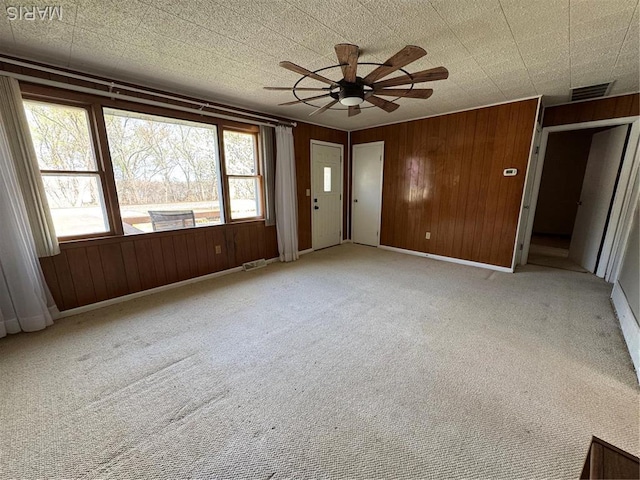 13899 Riverview Dr, New London, MO 63459 - empty room with a ceiling fan, wooden walls, light colored carpet, and baseboards