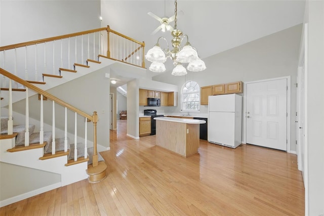 7426 Whitehall Colonial Ln, Saint Louis, MO 63119 - kitchen with black appliances, a center island, light wood-style floors, high vaulted ceiling, and light countertops