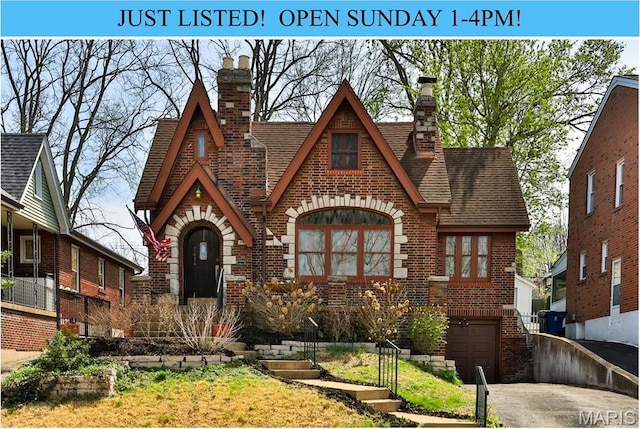 7414 Bruno Ave, Saint Louis, MO 63117 - english style home featuring brick siding, a chimney, a garage, driveway, and a shingled roof