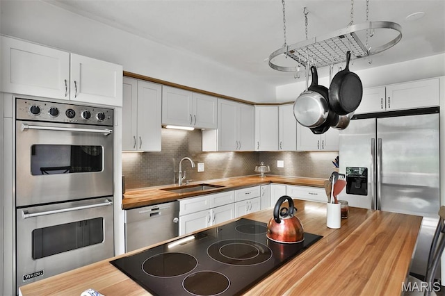 7414 Bruno Ave, Saint Louis, MO 63117 - kitchen featuring butcher block counters, stainless steel appliances, a sink, and tasteful backsplash