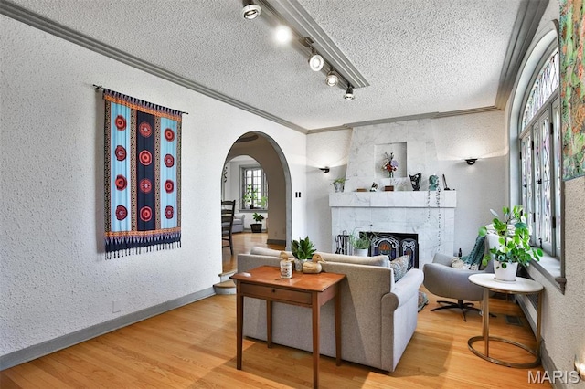 7414 Bruno Ave, Saint Louis, MO 63117 - living area with ornamental molding, a textured ceiling, arched walkways, a textured wall, and wood finished floors