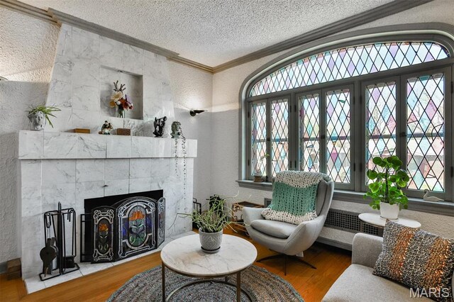 7414 Bruno Ave, Saint Louis, MO 63117 - sitting room with a textured ceiling, wood finished floors, a textured wall, ornamental molding, and a tile fireplace