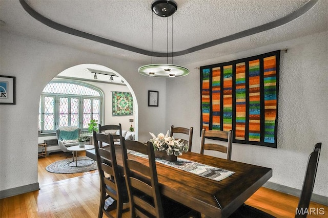 7414 Bruno Ave, Saint Louis, MO 63117 - dining room featuring a raised ceiling, a textured ceiling, wood finished floors, a textured wall, and baseboards