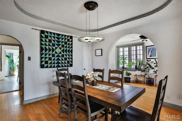 7414 Bruno Ave, Saint Louis, MO 63117 - dining room with arched walkways, a textured ceiling, light wood finished floors, baseboards, and ceiling fan