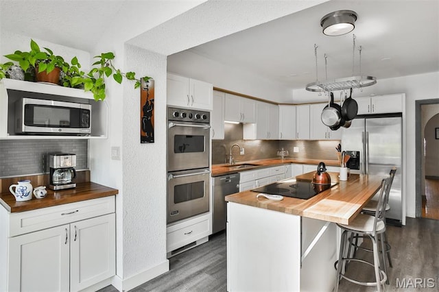 7414 Bruno Ave, Saint Louis, MO 63117 - kitchen featuring appliances with stainless steel finishes, wood counters, a sink, dark wood-type flooring, and decorative backsplash