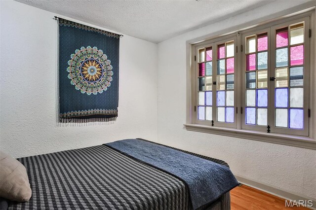 7414 Bruno Ave, Saint Louis, MO 63117 - bedroom with a textured wall, a textured ceiling, and wood finished floors