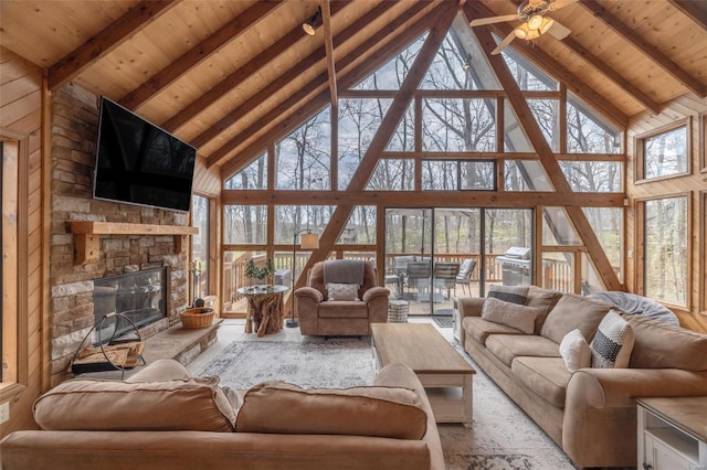 living room featuring high vaulted ceiling, beam ceiling, wood ceiling, a stone fireplace, and a ceiling fan