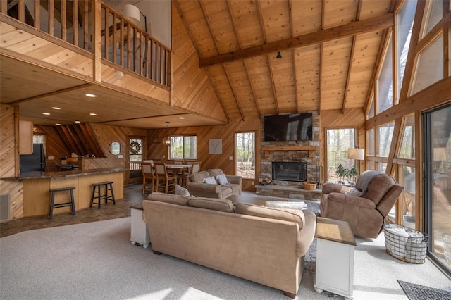 carpeted living room with wooden walls, high vaulted ceiling, beamed ceiling, wooden ceiling, and a fireplace