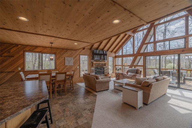 living area featuring wood walls, wood ceiling, a stone fireplace, high vaulted ceiling, and recessed lighting