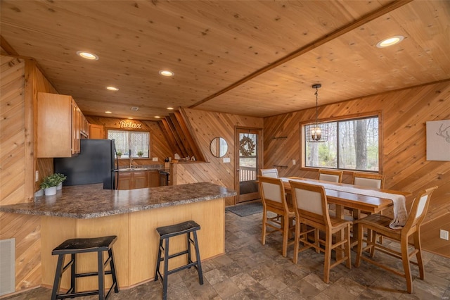 kitchen featuring freestanding refrigerator, wood walls, healthy amount of natural light, a peninsula, and wooden ceiling
