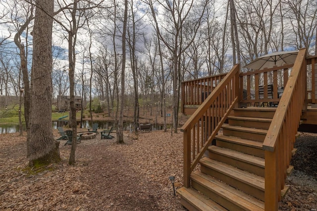 view of yard featuring a fire pit, stairs, and a deck with water view