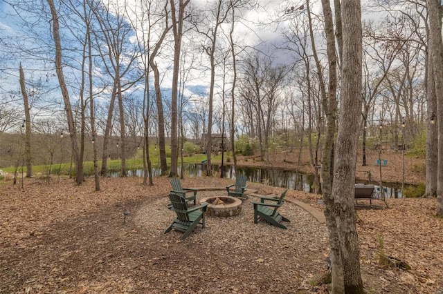 view of yard with an outdoor fire pit and a water view