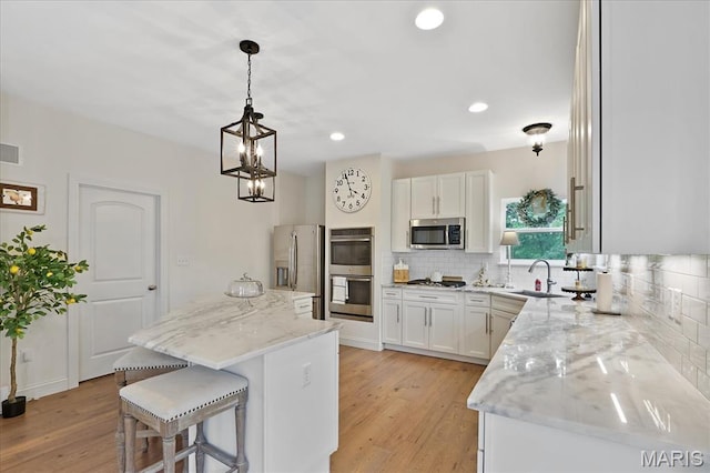 472 Cypress Creek Ln, Imperial, MO 63052 - kitchen with stainless steel appliances, light wood-type flooring, a kitchen breakfast bar, backsplash, and recessed lighting