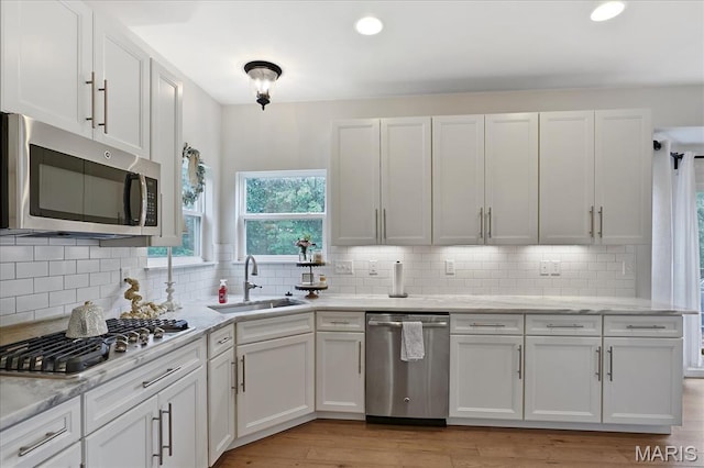 472 Cypress Creek Ln, Imperial, MO 63052 - kitchen with appliances with stainless steel finishes, a sink, white cabinets, decorative backsplash, and light wood finished floors