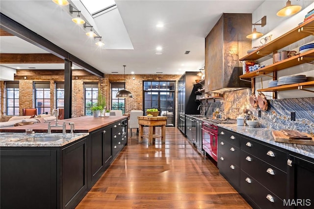 429 N Euclid Ave, Saint Louis, MO 63108 - kitchen featuring a sink, dark cabinetry, wood finished floors, brick wall, and decorative backsplash