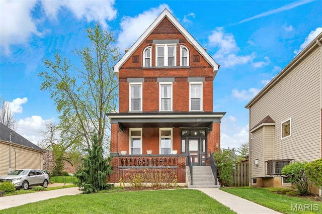 view of front of house featuring brick siding, a front lawn, and a porch
