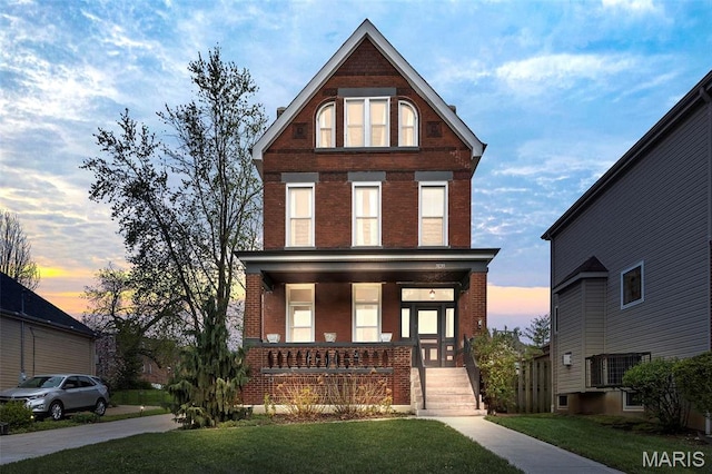 view of front of house featuring brick siding, covered porch, and a front lawn