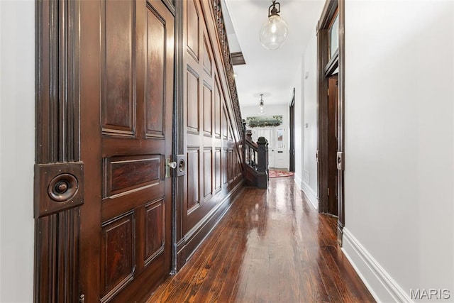 corridor featuring dark wood-type flooring and baseboards