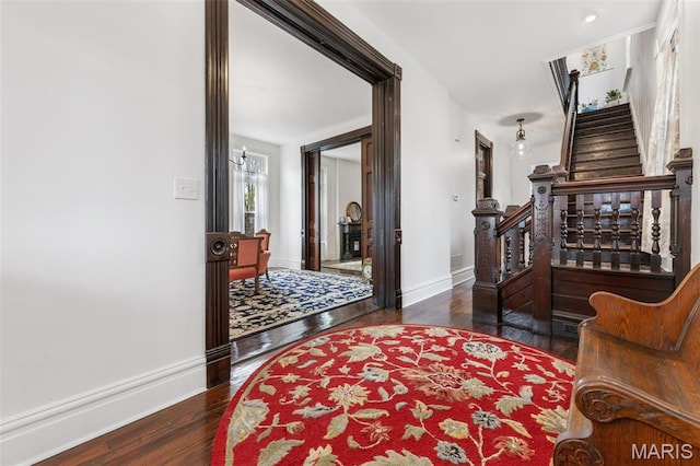 corridor with stairs, wood finished floors, and baseboards