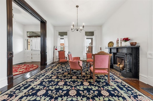 dining space featuring wood finished floors, a chandelier, a fireplace with flush hearth, and baseboards