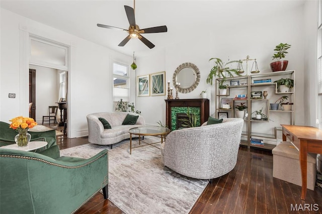 living area with a fireplace, ceiling fan, and hardwood / wood-style flooring