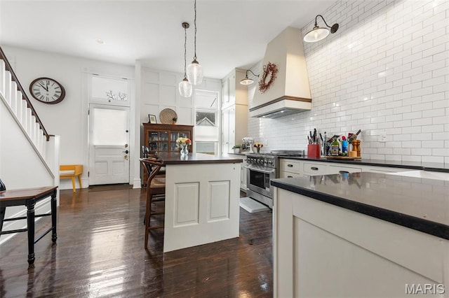 kitchen featuring stainless steel range, custom exhaust hood, dark countertops, and tasteful backsplash