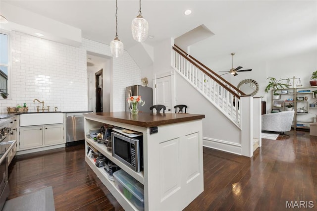 kitchen with appliances with stainless steel finishes, a sink, a ceiling fan, decorative light fixtures, and dark wood-type flooring