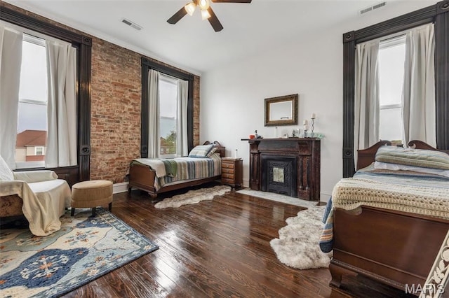 bedroom featuring hardwood / wood-style flooring, a fireplace, brick wall, and ceiling fan