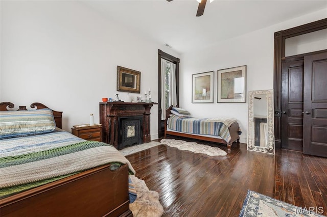 bedroom with hardwood / wood-style flooring, ceiling fan, baseboards, and a fireplace with flush hearth