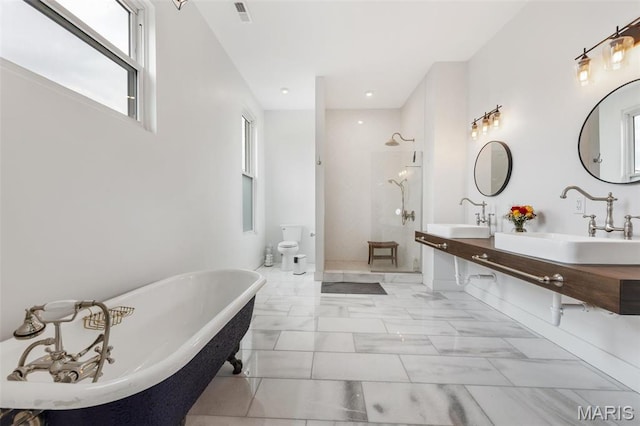 full bath featuring marble look tiles, walk in shower, a freestanding bath, double vanity, and recessed lighting