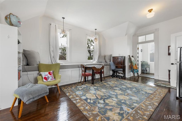 sitting room with hardwood / wood-style floors, vaulted ceiling, and a chandelier