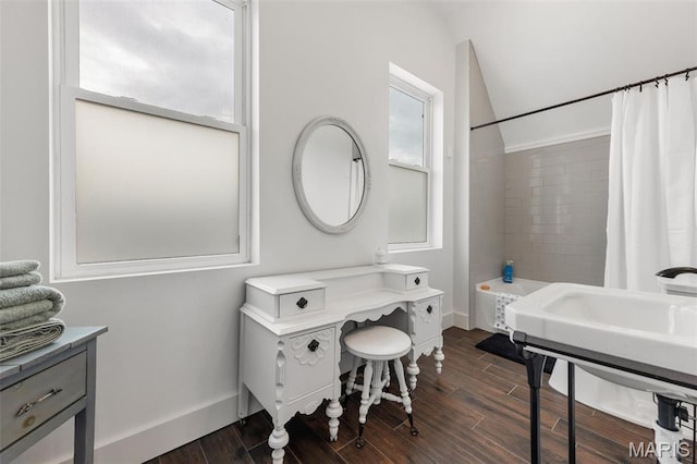 full bath featuring wood finished floors, baseboards, vaulted ceiling, and shower / bath combo with shower curtain