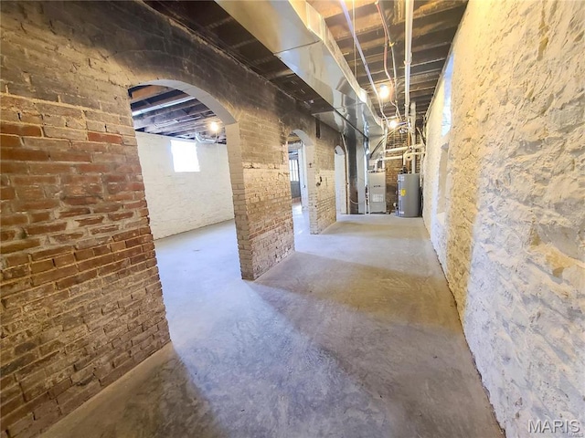 basement with water heater, arched walkways, and heating unit