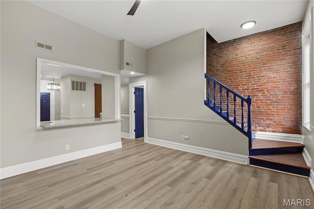 914 Russell Blvd, Saint Louis, MO 63104 - unfurnished living room with brick wall, wood finished floors, stairway, a towering ceiling, and a chandelier
