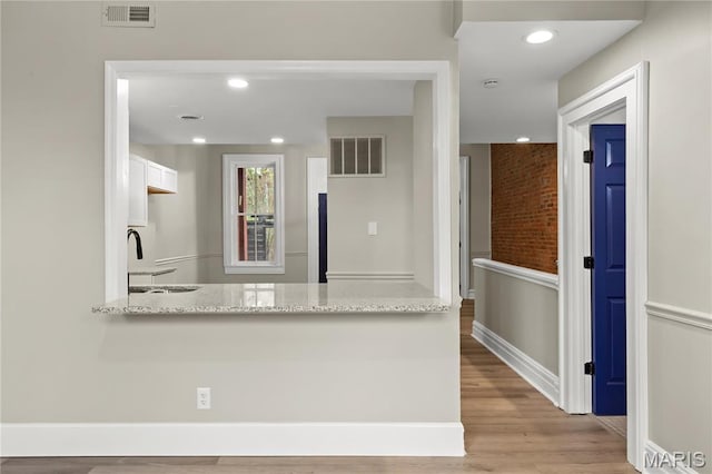 914 Russell Blvd, Saint Louis, MO 63104 - kitchen featuring white cabinetry, a peninsula, light stone countertops, wood finished floors, and recessed lighting
