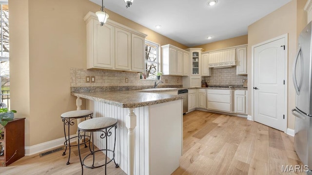 304 Wood Duck Ct, Waterloo, IL 62298 - kitchen with a peninsula, stainless steel appliances, a kitchen breakfast bar, a sink, and light wood-style flooring