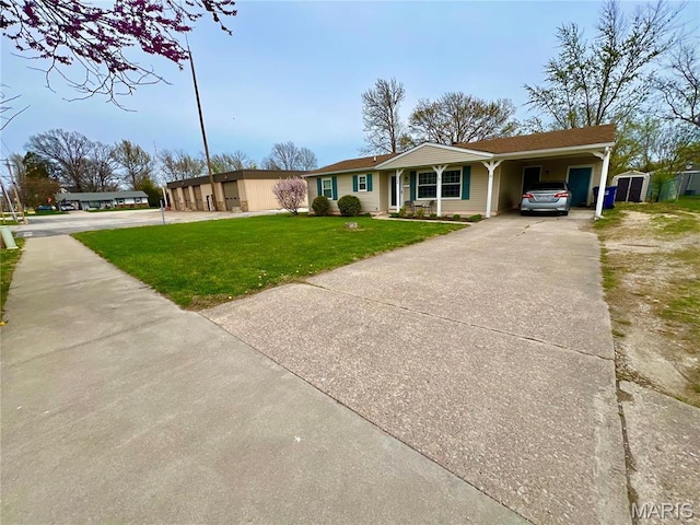 ranch-style house featuring a front yard, a shed, driveway, an attached carport, and an outbuilding