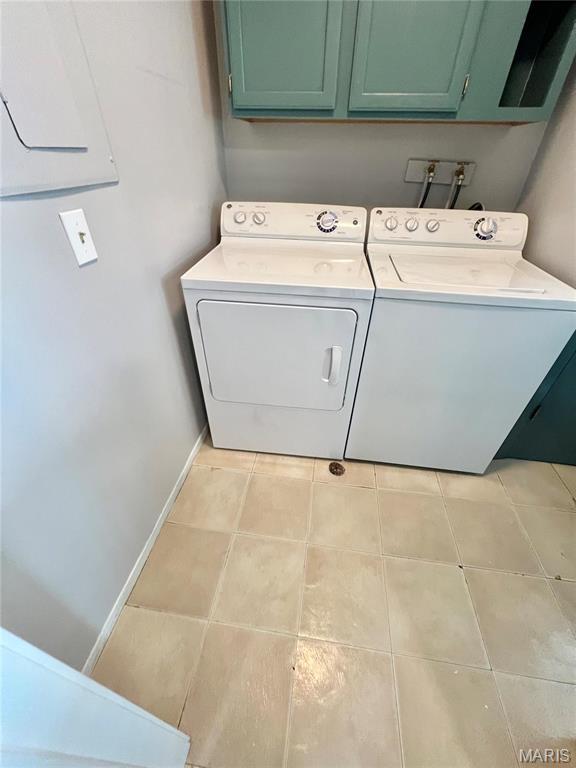 clothes washing area featuring cabinet space, separate washer and dryer, light tile patterned floors, and baseboards