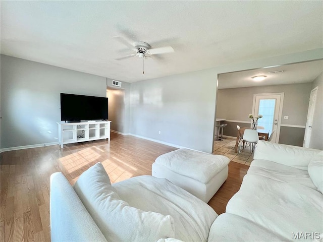 living area featuring a ceiling fan, wood finished floors, and baseboards