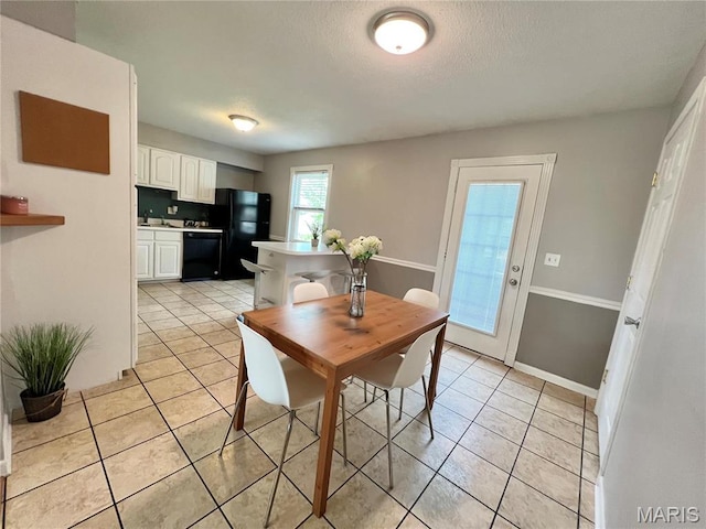 dining space with light tile patterned floors, a textured ceiling, and baseboards