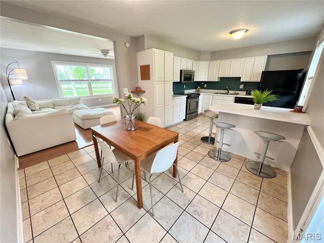 kitchen featuring a sink, stainless steel appliances, white cabinetry, and light tile patterned floors