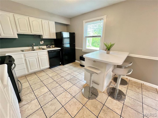 kitchen with black appliances, light countertops, a sink, white cabinets, and light tile patterned flooring