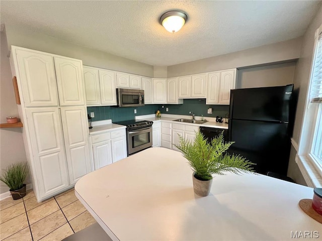 kitchen featuring appliances with stainless steel finishes, a sink, white cabinets, light countertops, and healthy amount of natural light