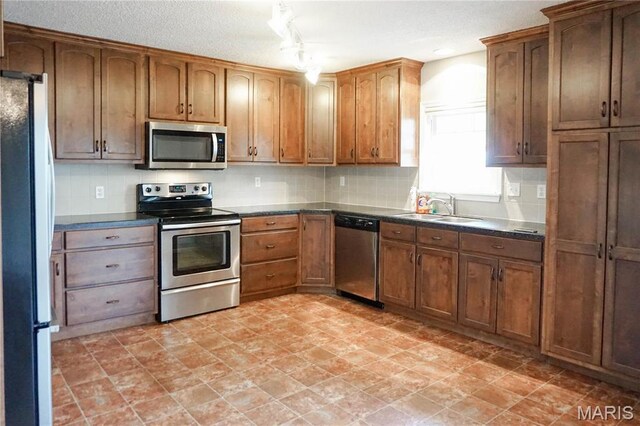 1502 Independence Rd, Rolla, MO 65401 - kitchen with appliances with stainless steel finishes, a sink, dark countertops, backsplash, and a textured ceiling