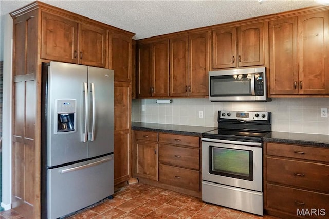 1502 Independence Rd, Rolla, MO 65401 - kitchen with appliances with stainless steel finishes, decorative backsplash, a textured ceiling, dark stone counters, and brown cabinetry